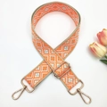 Detail of adjustable orange and grey geometric woven shoulder strap with gold metal hooks - Orange on Beige