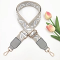 Detail of grey wide woven shoulder strap with leaf pattern and golden metal buckle clips - Beige Base Grey