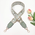 Detail of green embroidered floral bag strap with gold metal buckles and leather ends - Bean Green on Beige