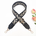 Close-up of jacquard bag strap featuring gray leaf patterns and gold metal swivel hooks - Dark Grey on Black