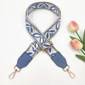 Detail of adjustable blue ethnic jacquard bag strap with gold metal hooks on white background - Beige Base Lake Blue