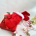 Nahaufnahme roter Samt-Weihnachtshandschuhe mit weißem Plüschrand auf einer Geschenkbox - Rot