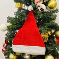 Klassische rote Weihnachtsmannmütze aus Plüsch an einem geschmückten Weihnachtsbaum für Feste - Rot