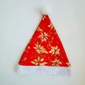 Dettaglio del cappello di Natale rosso con motivo a stella di Natale dorata e pompon bianco - Stile Fiore di Stella di Natale Rosso