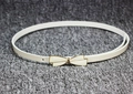 Detail of white patent leather skinny belt with golden bow buckle and adjustable holes - White