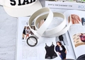 Détail d'une fine ceinture en similicuir blanc avec une boucle ronde en métal gris foncé - Blanc