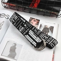 Detail of a black and white canvas belt with double D-ring buckle on a fashion magazine - Black