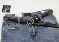 Detail view of a black slim leather belt with a golden double ring buckle on blue jeans - Black (Gold Buckle)