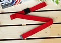 Détail d'une ceinture en nylon rouge avec boucle en plastique noir mat sur bois - Rouge