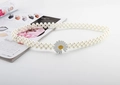 Detail of daisy buckle on elastic white pearl belt next to a fashion magazine - Daisy Silver Buckle Pearl Belt