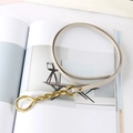 Close-up of beige leather belt with herringbone stitching and golden double-ring buckle - Gray