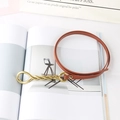 Detail of thin brown leather belt with gold twisted knot buckle on a fashion magazine - Khaki