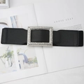 Detail view of black elastic wide belt with a luxury rhinestone encrusted buckle on magazine - Black