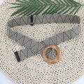 Detail of hand-woven geometric belt with natural round wooden buckle on textured background - Color Block