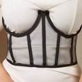 Detail view of black mesh corset belt with metal rings and lace-up straps over white dress - Black