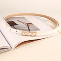 Fashionable white leather belt with gold geometric buckle displayed on a magazine - White