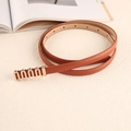 Detail of slim brown leather belt with wavy gold metal buckle on a minimalist background - Khaki