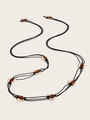 Dettaglio della cintura intrecciata boho Y2K con perle ambrate e anelli bianchi su corda - Nero