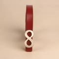 Dettaglio cintura sottile in pelle rossa con fibbia dorata a forma di otto su beige - Rosso