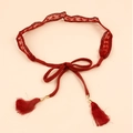 Detailed macro view of red lace weaving and ethnic tassel pendants on the slim belt - Red