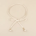 Dettaglio di cintura intrecciata bianca boho con pendenti in perla e chiusure dorate - Bianco