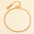 Dettaglio della catena dorata da vita con maglie cubane e pendente con nappe in metallo - Oro
