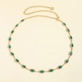 Detailed macro view of gold chain belt featuring marquise-cut emerald stones with zircon halo - Gold