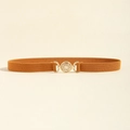 Dettaglio della cintura elastica marrone con fibbia dorata rotonda e rilievo geometrico vintage - Cammello