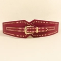 Detalle de cinturón corsé de cuero rojo con tachuelas doradas y hebilla rectangular - Burdeos