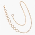 Dettaglio di una catena in vita dorata a forma di cuore con strass scintillanti su bianco - Oro