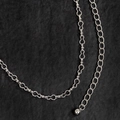 Detailopname van een zilveren metalen tailleketting met golvende schakels en een bolhanger - Zilver (Kalebas Kraal)