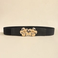 Close-up of black elastic waist belt featuring luxury gold floral buckle on beige texture - Black & Gold