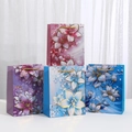 Luxury floral gift bags with gold foil lily patterns and woven handles in four colors - 4 Designs Mixed / 23x18x10cm