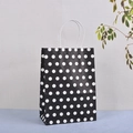Détail d'un sac cadeau en papier kraft noir à pois blancs avec poignées torsadées - Noir