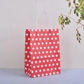 Détail d'un sac cadeau à pois rouges et blancs avec poignées en cordelette blanche - Rouge