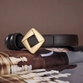 Dettaglio di una sottile cintura in pelle con fibbia geometrica in oro opaco su rivista - 100 / caffè