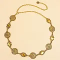 Detail view of vintage gold metal waist chain with embossed patterns and camellia charm - Antique Gold