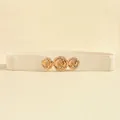Detailed view of three golden metal rose buckles on a cream elastic waist belt - Beige / 63cm