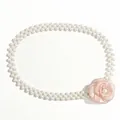 Dettaglio dell'elegante cintura di perle a doppia fila con un fiore di camelia rosa - Rosa