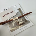 Close-up of slim brown leather belt with elegant pearl clover buckle on a magazine - Brown