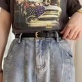 Détail d'une ceinture en cuir noir vintage avec boucle en C dorée sur un jean - Noir