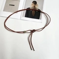 Detailansicht der ziegelroten geflochtenen Lederkordeln mit silberner Metallschnalle - Braun