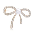 Élégante broche nœud dorée avec des strass étincelants et une perle blanche sur fond blanc - Or