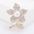 Dettaglio dell'elegante spilla floreale dorata con perle bianche e strass scintillanti raffinati - Oro