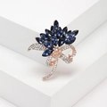 Broche floral con cristales azul oscuro y lazo de oro rosa sobre un soporte blanco - Dorado