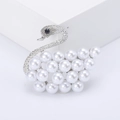 Elegant swan shaped brooch with white pearls and sparkling rhinestones on a white pedestal - Silver