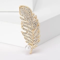 Dettaglio della spilla a piuma dorata con strass scintillanti e un'elegante perla bianca - Oro