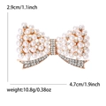 Elegant bow brooch with pearls and rhinestones on a gold-plated base, size 4.7cm x 2.9cm - Gold