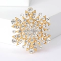 Macro di una spilla a fiocco di neve dorata con strass bianchi e dettagli metallici finemente lavorati - Oro