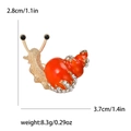 Broche de caracol en esmalte naranja con pedrería blanca sobre metal dorado, 3.7cm - Naranja